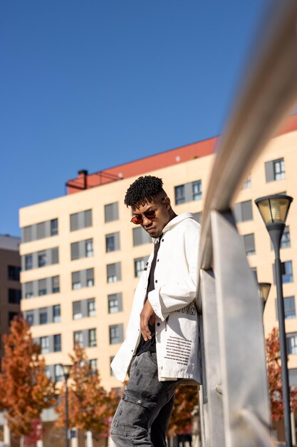 Latin black man with sunglasses on the street looking down urban vertical portrait