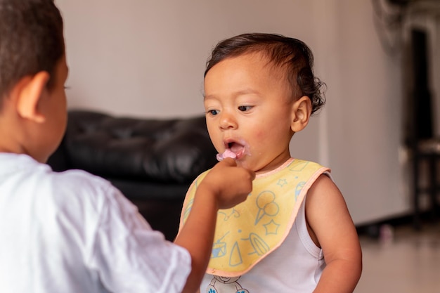 Latin boy feeding his younger brother Tender brothers sharing food