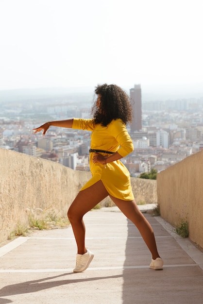 Latin brunette woman of laughs with yellow clothes dances in the background the city outdoors