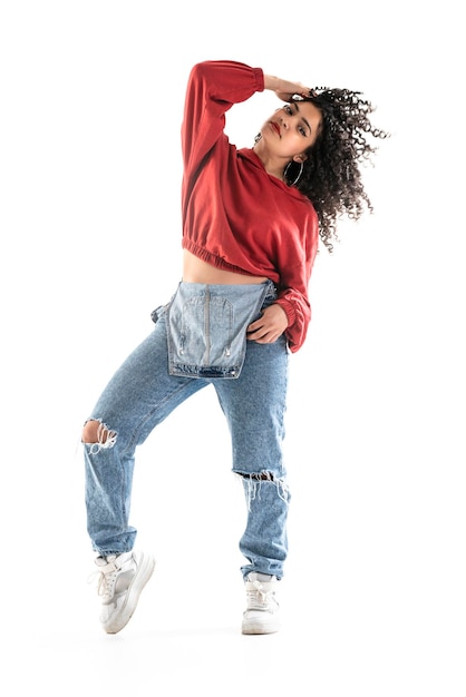 Latin brunette woman with curly hair is dancing in studio with white background