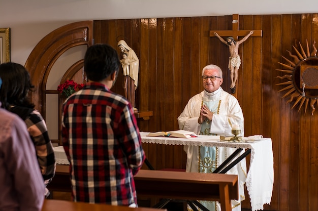 латинско-католический священник проповедует в церкви во время литургии в разных позах
