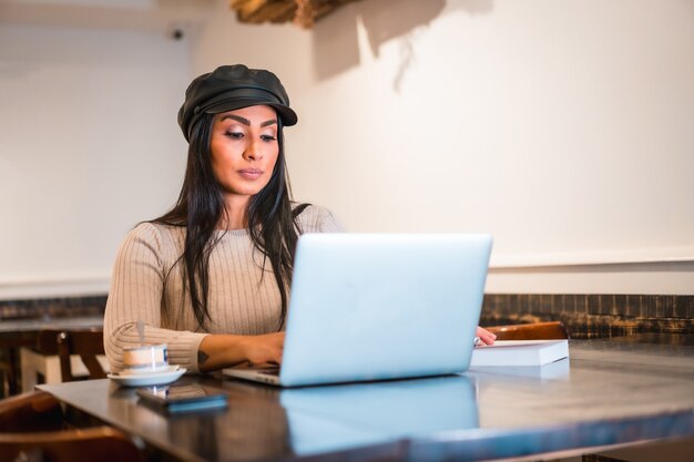 Latin fashion designer making some designs in a cafeteria with her laptop