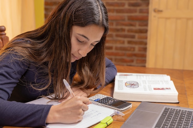 学用品を持ってテーブルで勉強するラテン系の女の子