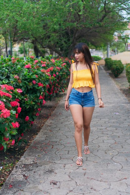 Latin girl walking in the park next to a flowering tree.