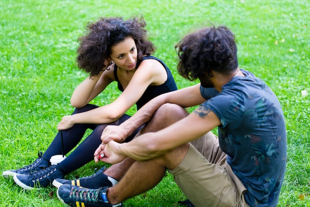 Latin Hipster couple sitting on meadow