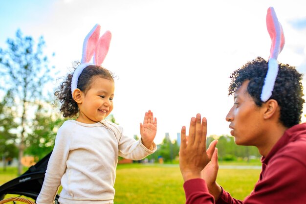 Latin hispanic father and mixed race little girl playing rabbit and hare outdoor