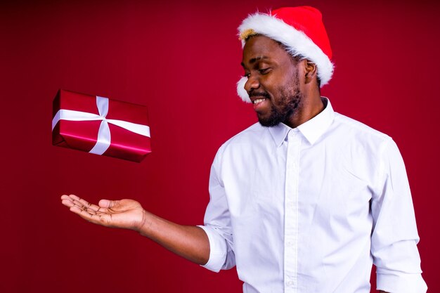 Latin hispanic man wearing santas hat in studio red background