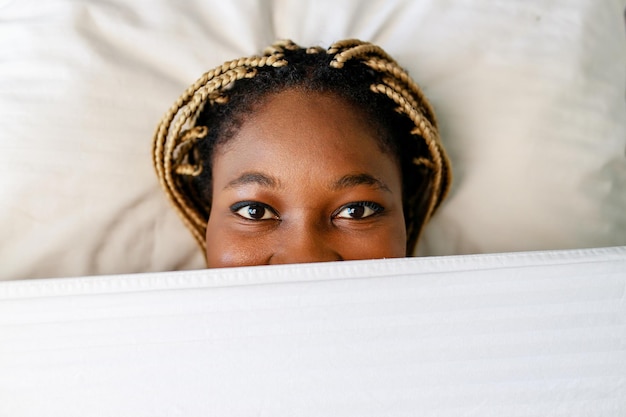 Latin hispanic woman hide behind the blanket in the morning at home