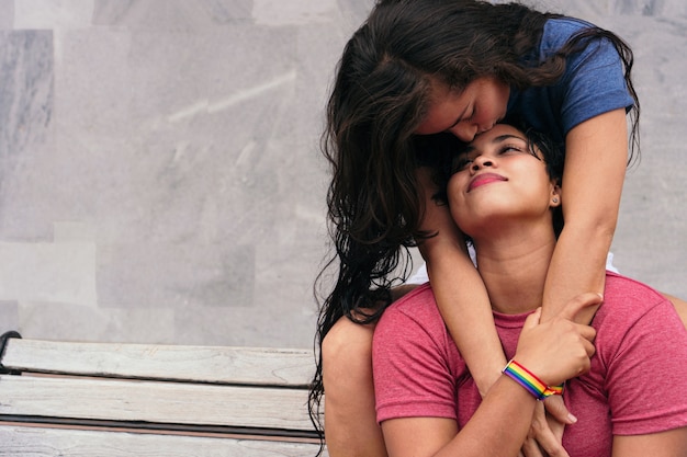 Latin Lesbian couple sitting on a bench in the park. LGBT Concept