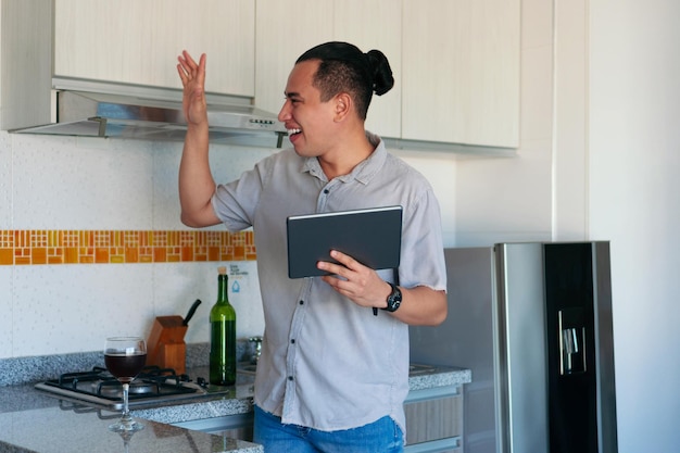 Latin man happy in the kitchen using a tablet