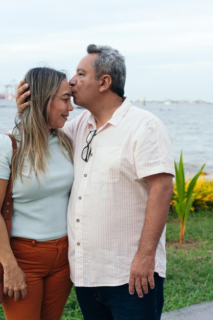 야외에서 그의 이마에 그의 아내에게 키스하는 라틴 남자