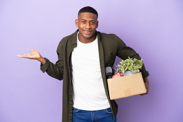 Latin man making a move while picking up a box full of things with shocked facial expression