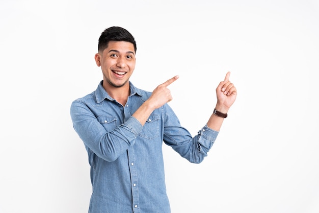 Latin man pointing with two fingers to the side and smiling
