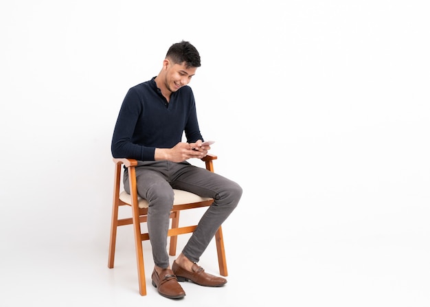 Latin man sitting with mobile phone in hands