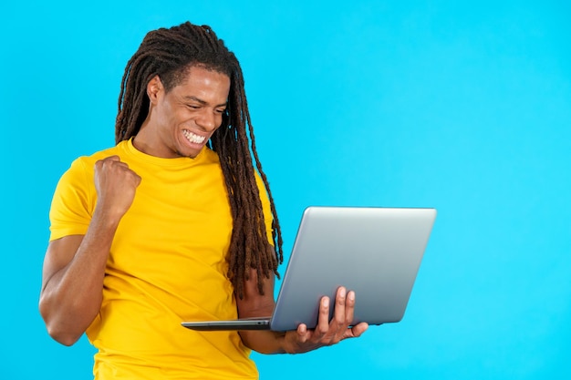 Latin man with dreadlocks celebrating while looking at the laptop