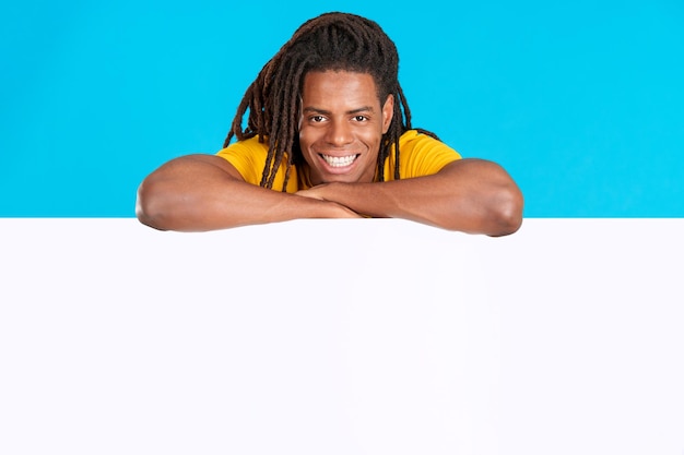 Latin man with dreadlocks leaning on a blank board