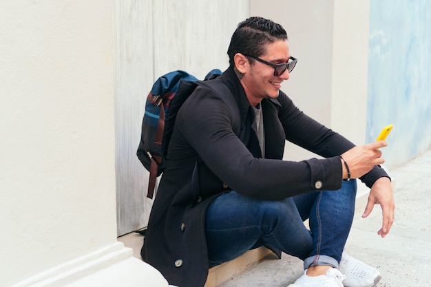 Latin man with smartphone on city street, checking cell phone