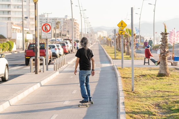 latin mature or senior man skateboard on bikeway in La Serena at sunset