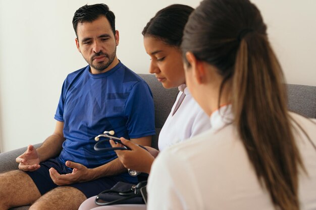 latin nurses checking a man39s blood pressure at home