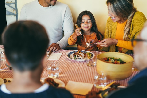 写真 家庭での夕食中に子供たちと楽しんでいるラテン系の親が女の子の顔に焦点を当てる