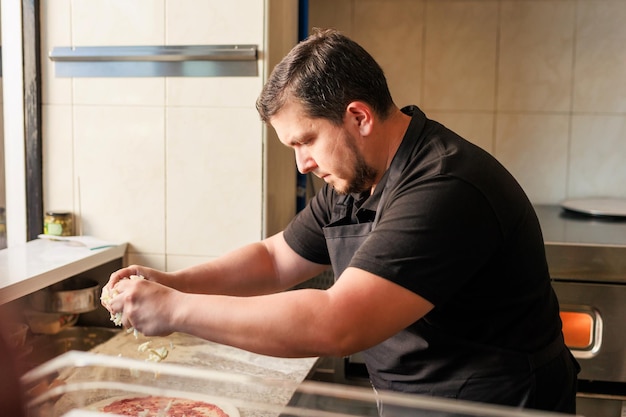 Lo chef pizzeria latino cucina la pizza in uniforme professionale ristorante imprenditore di cucina italiana