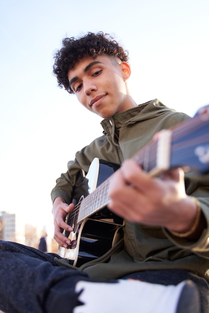 Latin teenager concentrating on playing guitar