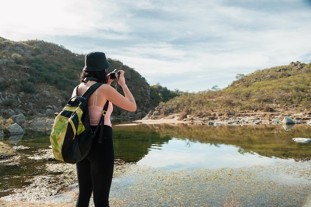 Latin tourist photographer young woman taking pictures of two mountains with her digital camera