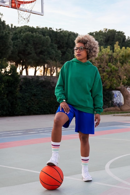 Donna latina su un campo da basket che tiene una palla con il suo piede concetto di sport urbano nello spazio della copia della strada per testo