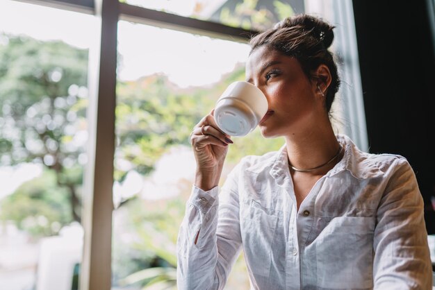 Латиноамериканка в кафе пьет кофе