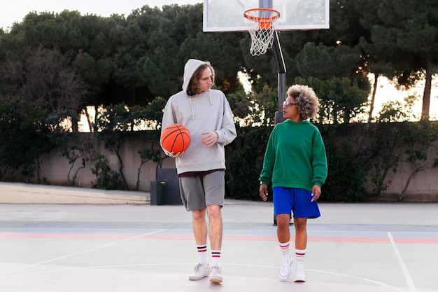 Latin woman and caucasian man chatting while walking on the basketball court after a game concept of friendship and urban sport in the street copy space for text