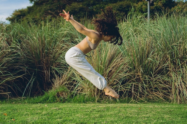 Latin woman dancer in nature jumps with her arms backwards and her legs forwards