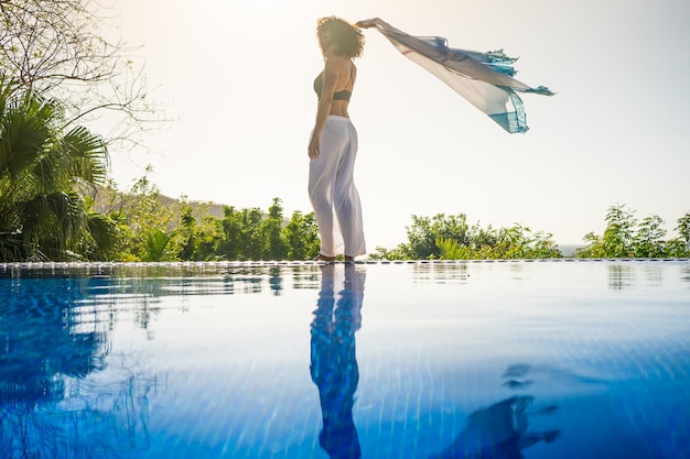 Latin Woman dancing next to an outdoor tropical pool