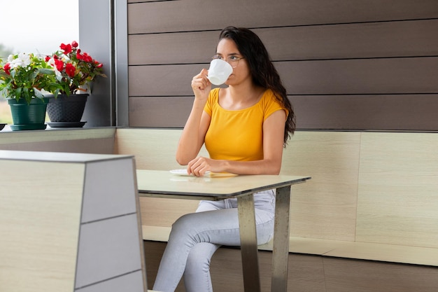 Foto donna latina che beve caffè nella caffetteria