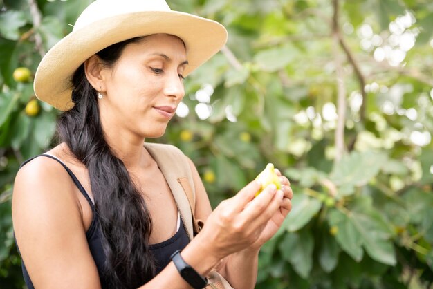 Фото Латинская женщина ест смоковницы рядом с смоковницей