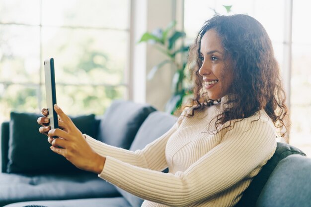 幸せな気持ちでタブレットでラテン女性のfacetimeまたはビデオ会議