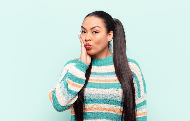 Latin woman feeling shocked and astonished holding face to hand in disbelief with mouth wide open