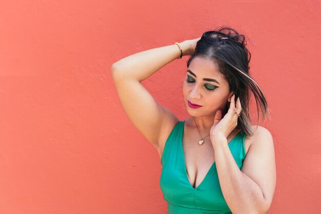 Latin Woman in green dress, standing in the street, eyes closed.