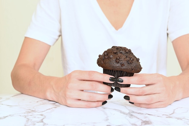 Latin woman holding muffin on light background