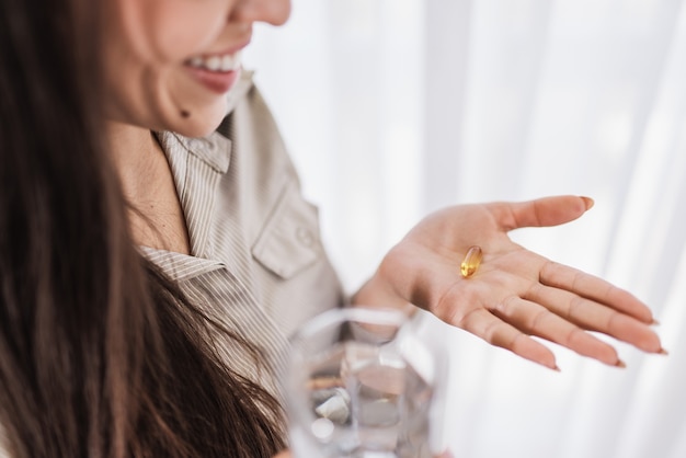 Latin woman holding a Omega 3 fish oil capsule at home.