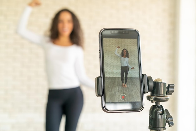 Latin woman influencer created her dancing video by smartphone camera. To share video to social media application.