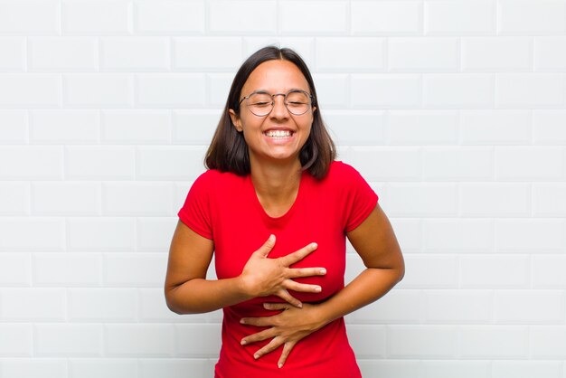 Latin woman laughing out loud at some hilarious joke, feeling happy and cheerful, having fun