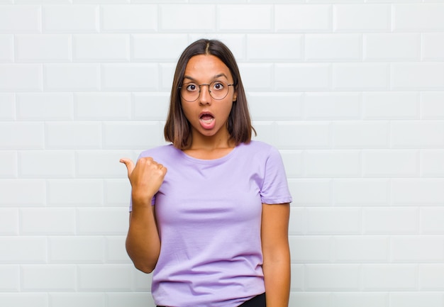 Latin woman looking astonished in disbelief, pointing at object on the side and saying wow, unbelievable