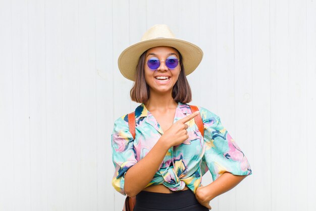 Latin woman looking excited and surprised pointing to the side and upwards to copy space