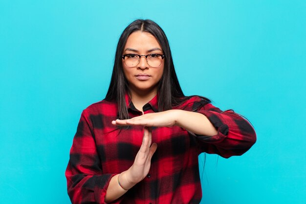 Photo latin woman looking serious, stern, angry and displeased, making time out sign