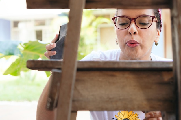 Latin woman polishing a chair with a sandpaper at home