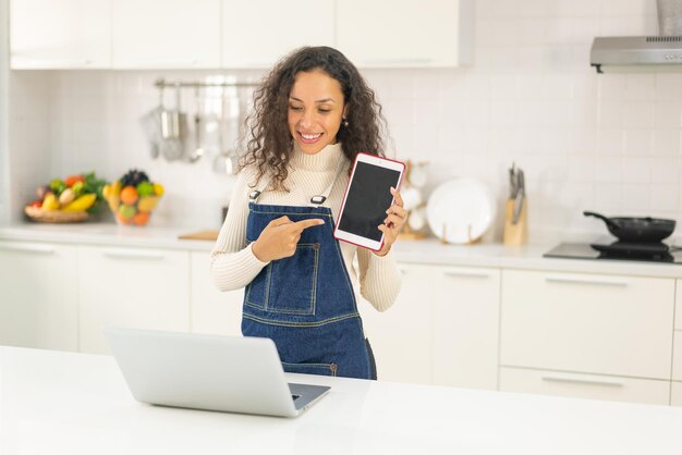 Latin woman shooting video and cooking at the kitchen for share on blog