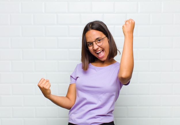 Latin woman shouting triumphantly, looking like excited, happy and surprised winner, celebrating