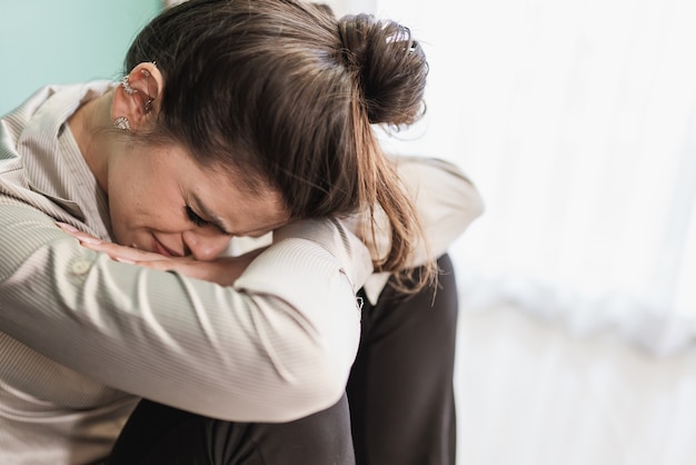 Latin woman sitting on floor feels unhappy by personal problems, break up or ruined marriage