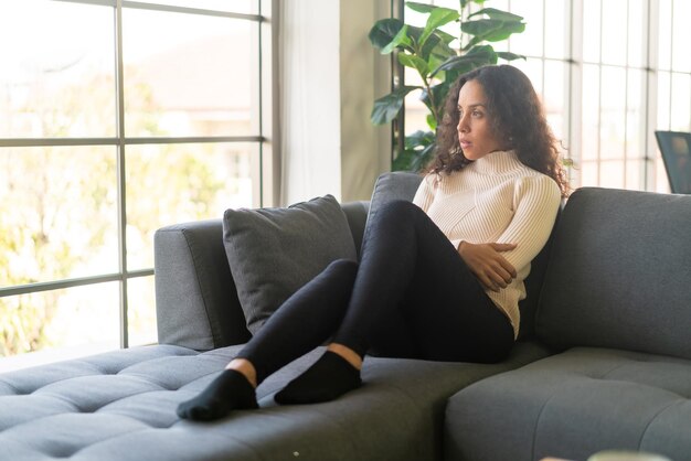 Latin woman sitting on sofa at home with lonely feeling