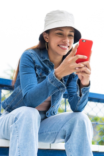 Latin Woman sitting on stairs and texting on her smartphone